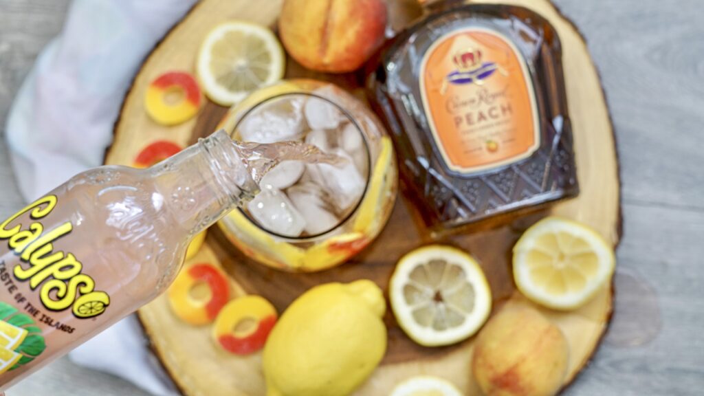pouring peach lemonade into crown royal peach whiskey drink