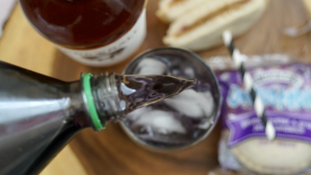 pouring grape soda into glass with peanut butter whiskey